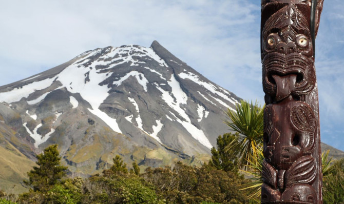 Pouwhenua (meaning carved wooden post marking a place of significance) in the foreground and large mountain in the background