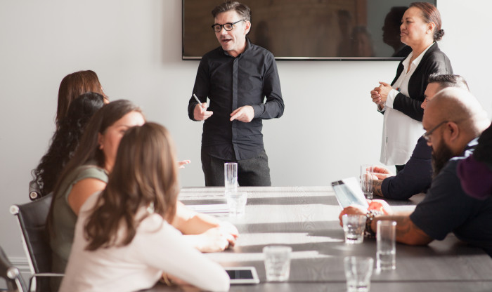 People sit at a table listening to a man speak