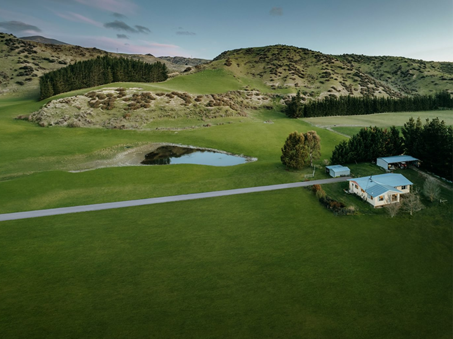 birds eye view of a rural house and land with a long straight driveway.