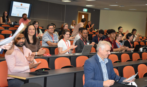 Students clapping at the end of a presentation in a lecture theatre 