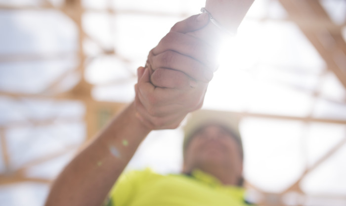 Close up of two people shaking hands with construction in the background