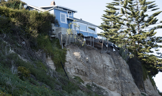 House hanging off the edge of a cliff where the land has slide away underneath it 