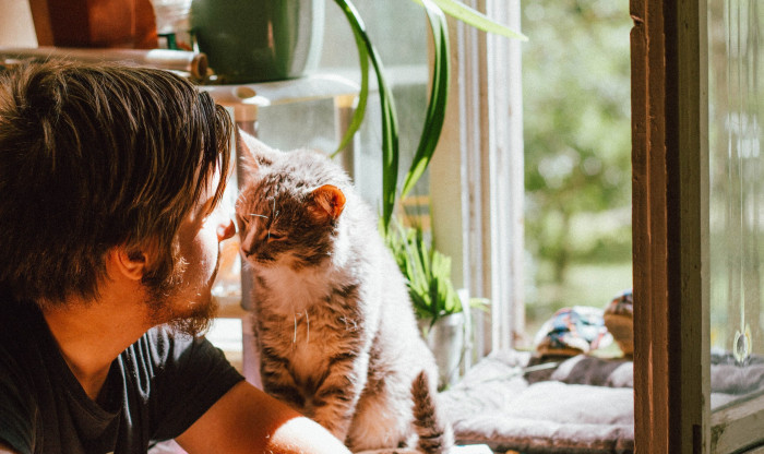 A man and his cat sit by the window